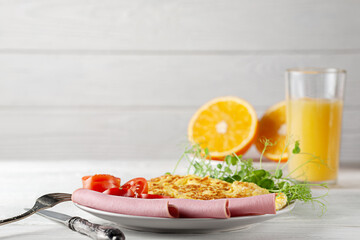 Light breakfast with sausage, omelettes, tomatoes and juice with oranges