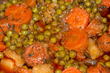  baked green peas with chopped carrots, potatoes and tomato sauce. selective focus. top view