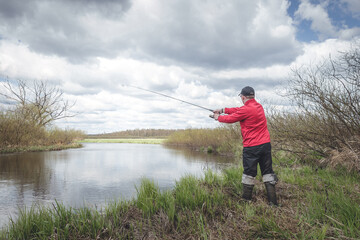 Fototapeta premium Fisherman in red clothes is fishing.