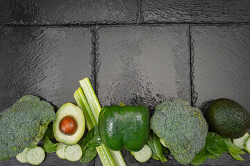 Fresh green vegetables and fruit on a slate board with copy space