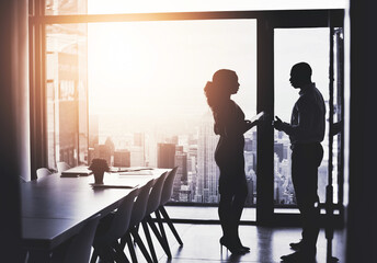 Theyve got clear visions for success. Silhouetted shot of two businesspeople having a discussion in...