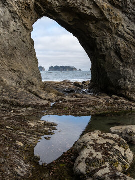 A large hole in a seaside cliff along the Pacific Northwest coast, park of Olympic National Park known as Hole-in-the-Wall on Rialto beach.