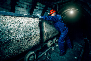 Tired miner in an old coal mine in the process of working. A miner in a blue protective suit with...