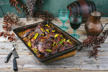 Traditional barbecue haunch of hare with leek in red wine sauce served as close-up in a rustic tray