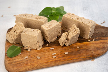 Traditional eastern sweets halva with sunflower seeds and mint leaves on a wooden cutting board. Close-up. Selective focus.