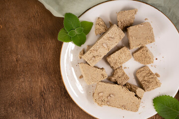 Traditional eastern sweets halva with sunflower seeds and mint leaves on a white plate. Top view. Selective focus.