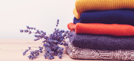 Home wardrobe with winter clothes. Woolen sweaters and dried lavender for protection from moth....