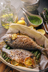 the concept of a delicious dinner for two from dorado. baked dorado fish with asparagus and lemon in spices
