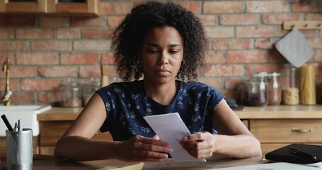 Worried young Black lady open envelop read official letter feel upset stressed with bad news loan rejection exam failure. Concerned millennial female being fired from job get dismissal order by mail