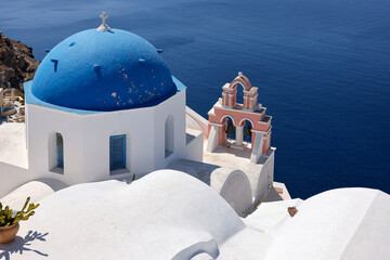 View from viewpoint of Oia village with blue dome of  greek orthodox Christian church. Santorini, Greece