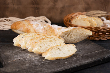 Slices of homemade fresh crispy baguette bread in a cutting board. Wooden background. Side view.