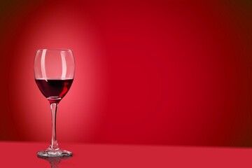 Red wine in the glass on the desk over red background