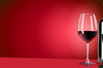 Red wine in the glass on the desk over red background