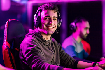 A happy video game champion playing video game at gaming room and smiling at the camera.