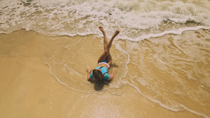 Crazy madwoman daring funny woman lying on shallow water sea. Top view happy slightly tipsy woman enjoying her vacation on a tropical island. Smiling girl funny posing. Concept summer holidays