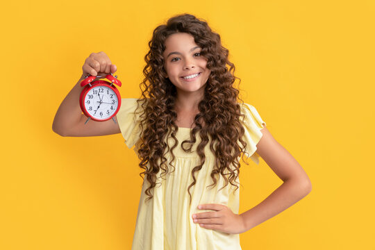 cheerful child with alarm clock. school kid curly hair showing clock. you are late. deadline.