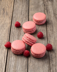 Berry macarons with raspberries over wooden table