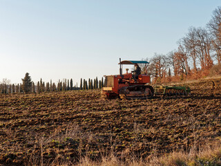 Fototapeta premium Agriculture,tractor preparing land with seedbed cultivator as part of pre seeding activities in early spring season of agricultural works at farmlands.