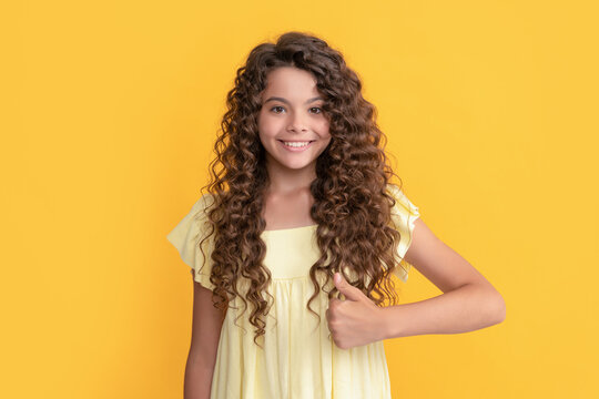 thumb up. smiling kid with curly hair. teen beauty hairstyle. female fashion model.