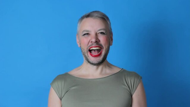 a gay man smiles broadly on an isolated blue background. lgbt. transgender