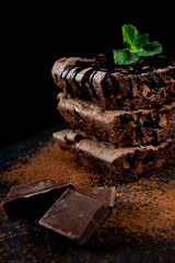 Delicious chocolate cake made with traditional recipe. Chocolate brownie, typical American. Decorated with mint leaves and cocoa. Dark food style.