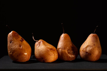 Overripe pears with black background and warm lighting.