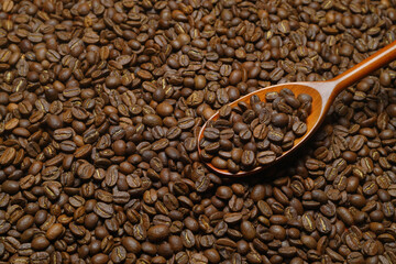 Coffee beans scattered close-up with a spoon.