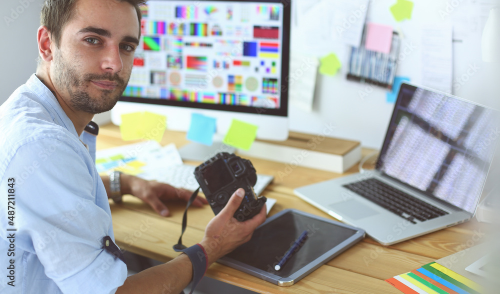 Poster portrait of young designer sitting at graphic studio in front of laptop and computer while working o