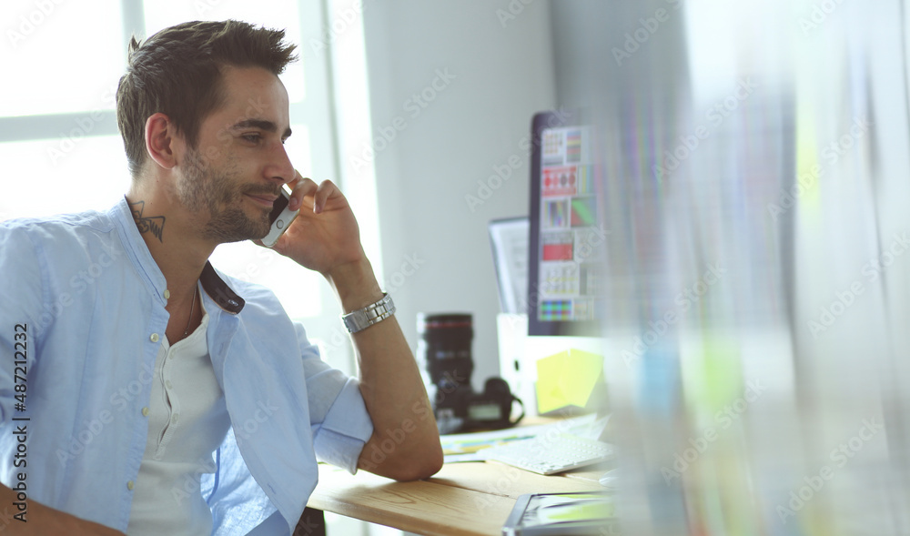 Poster portrait of young designer sitting at graphic studio in front of laptop and computer while working o