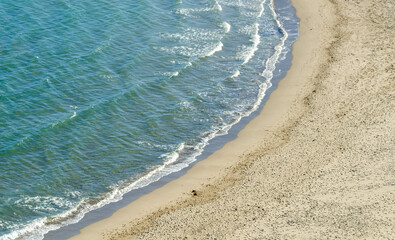 Top view on the sandy beach and turquoise mediterranean sea, beautiful waves and footprints on the sand