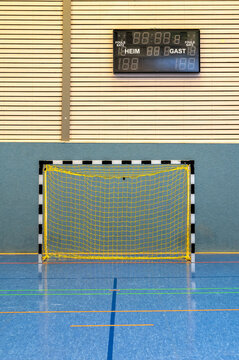 Moderne Sporthalle mit Handballtor und Anzeigetafel in deutscher Sprache mit den Worten Heim und Gast