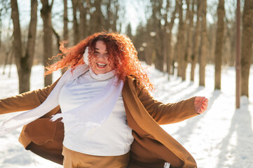 Cheerful fat caucasian woman walks in the park in winter.