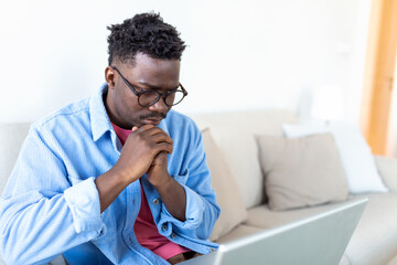 Handsome Black African American Specialist Working on Laptop Computer in Creative Home Living Room. Freelance Male is Doing Market Analysis and Creates Report with Charts for Clients and Employer.