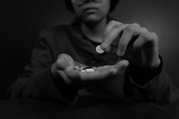 Child sad with pills in his hand. Medicine for depression, fever, stomach pain. Black and white.