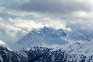 Fototapeta na wymiar Snow covered Alps peak with cloudy sky background during winter day.