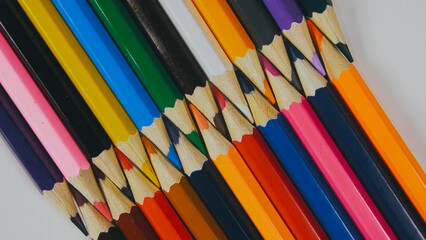 Many colored pencils are arranged around the edges of the image as a frame. In the center is an empty background with space for text. Mock up with copy space.