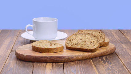 slices of rye bread with seeds and a white mug with a saucer on a wooden board
