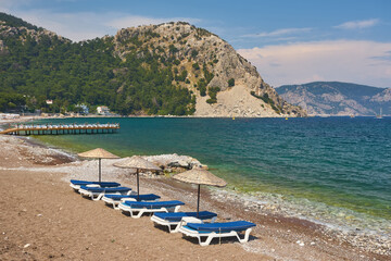 Fototapeta na wymiar sandy beach without people and with sun loungers, umbrellas, palm trees, Marmaris