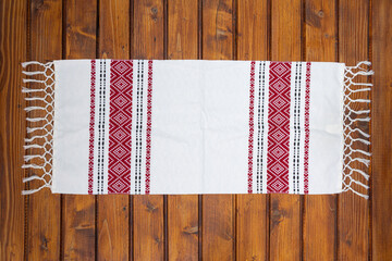 Traditional Romanian napkin or dish towel on empty wooden table. Traditional motif. Top view.