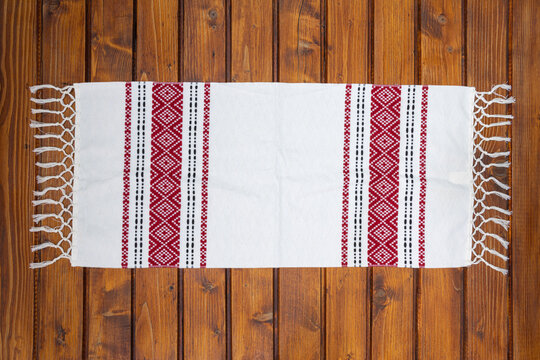Traditional Romanian napkin or dish towel on empty wooden table. Traditional motif. Top view.