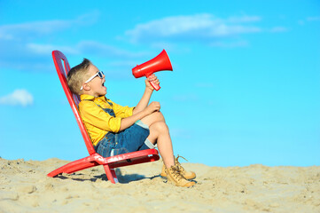 Little boy with a megaphone against the blue sky.