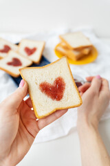 The girl makes a toast on which the heart is made of jam. Surprise breakfast concept in bed. Romance for St. Valentine's Day,