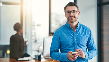 I always work with technology in hand. Portrait of a mature businessman standing in an office with...