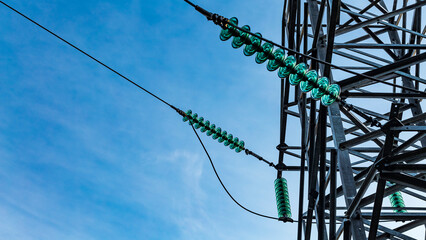 Close up of a transparent turquoise high voltage insulator or isolator in sunlight on electric...
