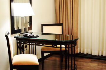 Mesa de trabajo en una habitación de hotel. Mesa con lámparas, sillas y teléfono.