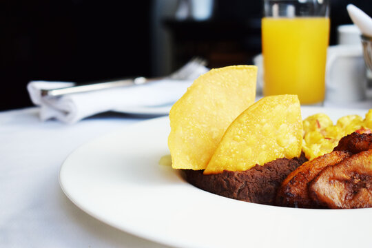 Desayuno tradicional Guatemalteco, servido con Huevos revueltos, frijoles volteados, nachos, pl&aacute;tanos fritos y jugo de naranja. Desayuno t&iacute;pico. Espacio para texto en la parte superior izquierda.