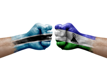 Two hands punch to each others on white background. Country flags painted fists, conflict crisis concept between botswana and lesotho