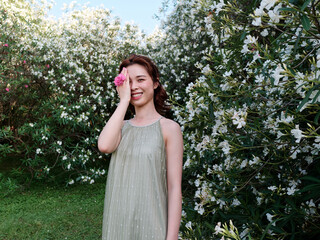 Portrait of young Asian woman standing in white oleander flower forest background, beautiful...