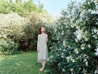 Portrait of young Asian woman standing in white oleander flower forest background, beautiful...