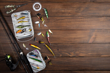 Fishing tackle - fishing spinning rod, hooks and lures on wooden background. Active hobby...